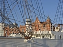 Segelschiff mit Ziegelgebäude im Hintergrund bei klarem Himmel.