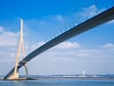 Schrägseilbrücke über ruhiges Gewässer unter blauem Himmel.