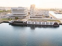 Flusskreuzfahrtschiff vor modernen Gebäuden im Hafen.