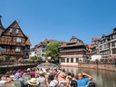 Menschen auf einem Ausflugsboot in einer Altstadt mit Fachwerkhäusern.