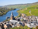 Stadtansicht mit Fluss und Weinbergen im Hintergrund.