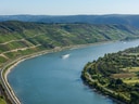 Fluss mit Weinbergen an den Hängen und einem Schiff auf dem Wasser.