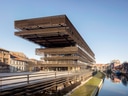 Modernes Gebäude über einem Kanal mit blauem Himmel.