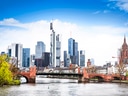Stadtansicht mit Fluss und Skyline modernen Gebäuden; rote Brücke im Vordergrund.