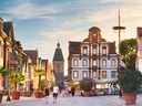 Historische Strasse mit alten Gebäuden und Menschen bei Sonnenuntergang.