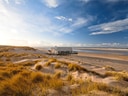 Haus am Strand in Dünenlandschaft bei Sonnenschein.