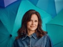Frau in Jeanshemd vor blauen Regenschirmen.