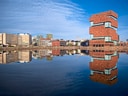 Moderne Gebäude spiegeln sich im Wasser unter blauem Himmel.