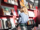 Person betrachtet Bücherregal in Buchhandlung.