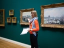 Frau präsentiert Gemälde in Kunstgalerie.