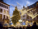 Weihnachtsmarkt mit Lichtdekorationen und grossen Gebäuden im Hintergrund.