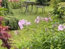 Garten mit Metalltisch, Stühlen und Blumen.