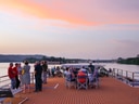 Menschen auf einem Flusskreuzfahrtschiff bei Sonnenuntergang.