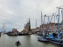 Hafenansicht mit Booten, historischer Turm und Gebäuden.