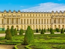 Historisches Gebäude mit gepflegtem Garten und Hecken im Vordergrund.