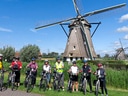 Gruppe von Radfahrern vor einer Windmühle.