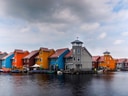 Bunte Häuser am Wasser unter wolkigem Himmel.