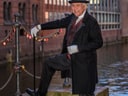 Mann in historischer Kleidung mit Zylinder und Stock am Kanal.