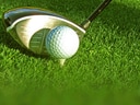 Golfschläger beim Abschlag auf grünem Rasen.
