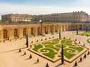 Barockgarten mit Blumenbeeten und Architektur im Hintergrund.