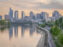Fluss mit Skyline von Hochhäusern bei Sonnenuntergang.