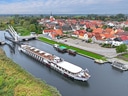 Kreuzfahrtschiff auf einem Fluss neben einer Stadt mit Brücke.