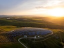 Luftaufnahme von Solarzellen auf hügeliger Landschaft bei Sonnenuntergang.
