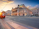 Strassenszene mit historischem Gebäude und Strassenbahn bei Sonnenuntergang.