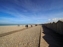 Kieselstrand mit Holzhütten unter klarem Himmel.