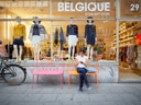Person sitzt vor Boutique Belgique auf Bank, daneben Fahrrad.