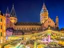 Beleuchteter Weihnachtsmarkt vor historischer Kathedrale in der Nacht.