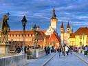 Menschen auf mittelalterlicher Brücke mit Kirche im Hintergrund.