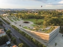Luftaufnahme eines modernen Gebäudes mit begrüntem Dach und umliegender Parklandschaft.
