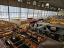 Markthalle mit zahlreichen bunten Marktständen und Menschen.