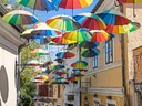 Gasse mit bunten Regenschirmen überkopf hängend.