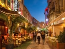 Belebte Strasse mit Cafés und Menschen am Abend.
