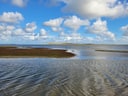 Wolken über der Nordsee mit Wattlandschaft.