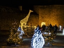 Weihnachtsbeleuchtung im Freien mit leuchtenden Tieren und Bäumen.