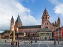 Historische Kathedrale mit Menschen auf einem Platz, unter blauem Himmel.