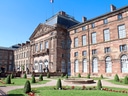 Historisches Gebäude mit gepflegtem Garten und Springbrunnen.