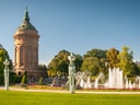 Wasserturm in einem Park mit Brunnen und Statuen.