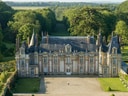 Historisches Schloss mit Türmen und weitläufigem Garten.