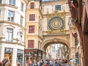 Strassenszene mit Uhrenturm und Menschen in einem Café.