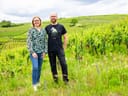 Zwei Personen stehen in einem grünen Weinberg.