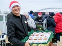 Mann mit Weihnachtsmütze hält Tablett mit Desserts auf Fest.