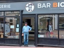 Mann steht vor einer Fromagerie namens Bar Bickett.