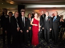 Gruppe von Musikern in festlicher Kleidung mit rotem Teppich im Hintergrund.
