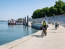 Radfahrer auf Uferweg am Fluss.