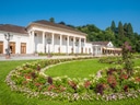 Historisches Gebäude mit formellen Gärten im Vordergrund.