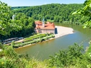 Kloster an Flussbiegung in grüner Landschaft.
